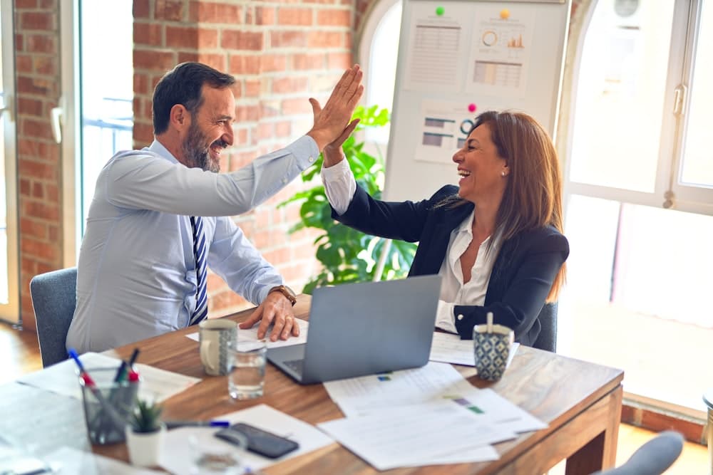 Two colleagues high-fiving at a desk