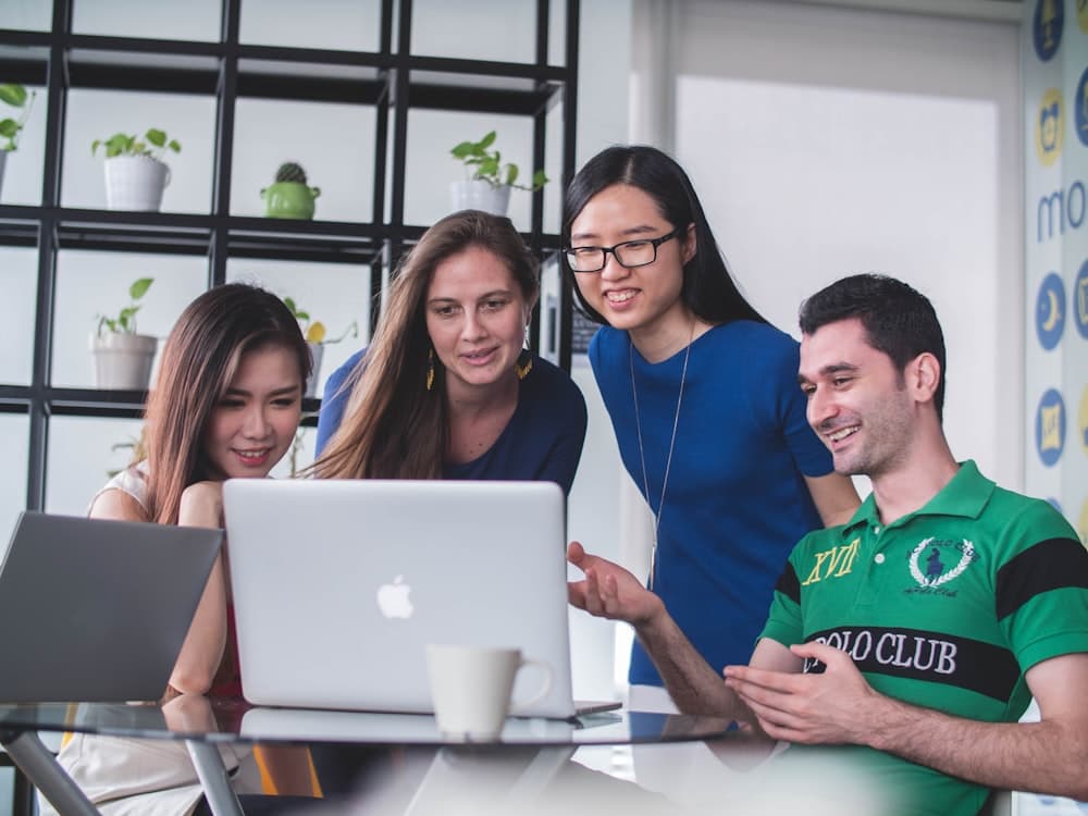 A group smiling around a laptop