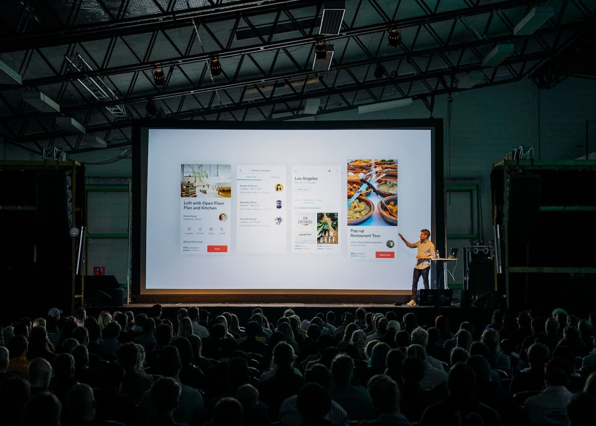 A speaker presenting to an audience with a large screen